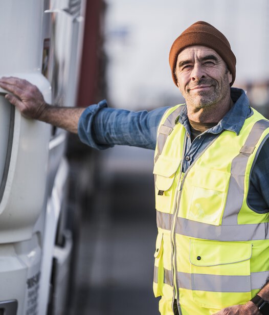 älterer Lkw-Fahrer mit Hand auf der Motorhaube
