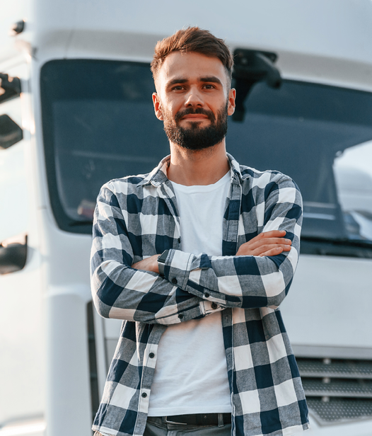 Ein junger Mann steht mit verschränkten Armen entspannt vor einem weißen LKW und lächelt in die Kamera.