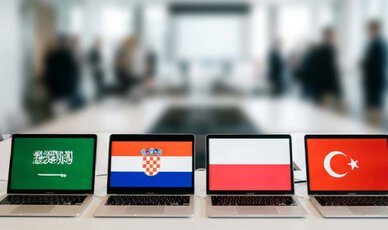 Laptops mit Flaggen stehen in einer Reihe auf dem Schreibtisch