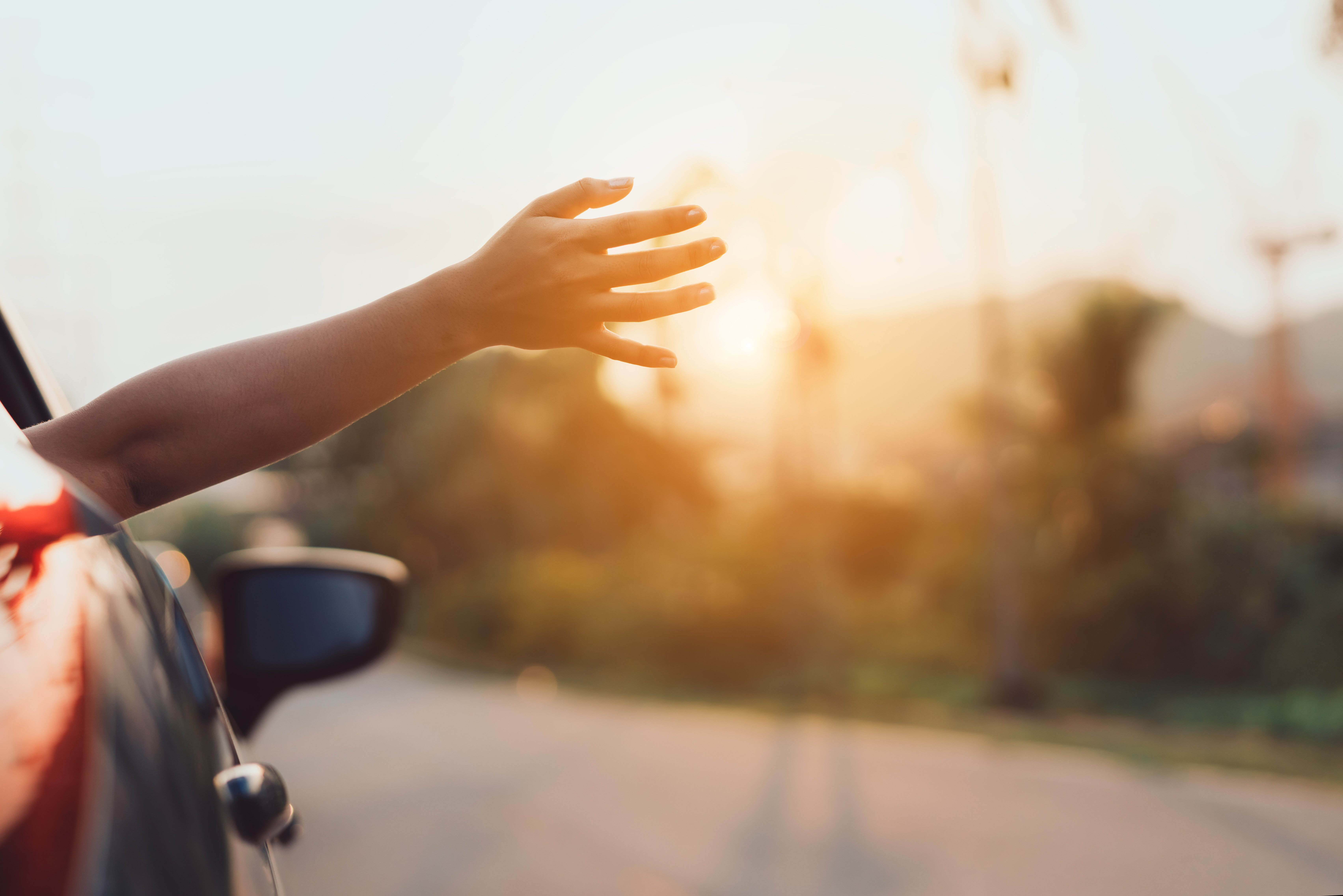 Hand wird bei Fahrt aus dem Autofenster gestreckt 