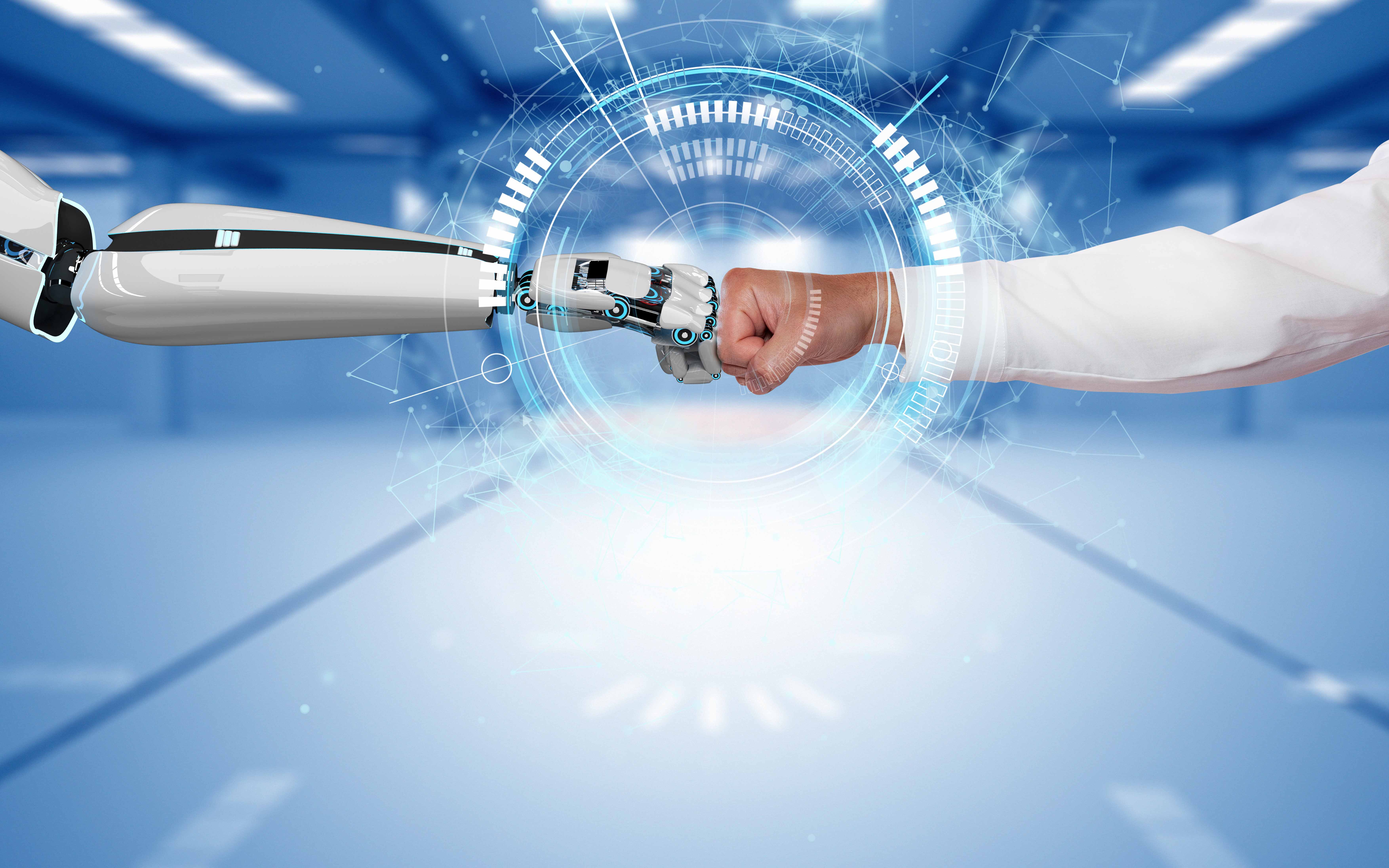 Roboterarm und Menschenarm berühren sich in der  Bildmitte 