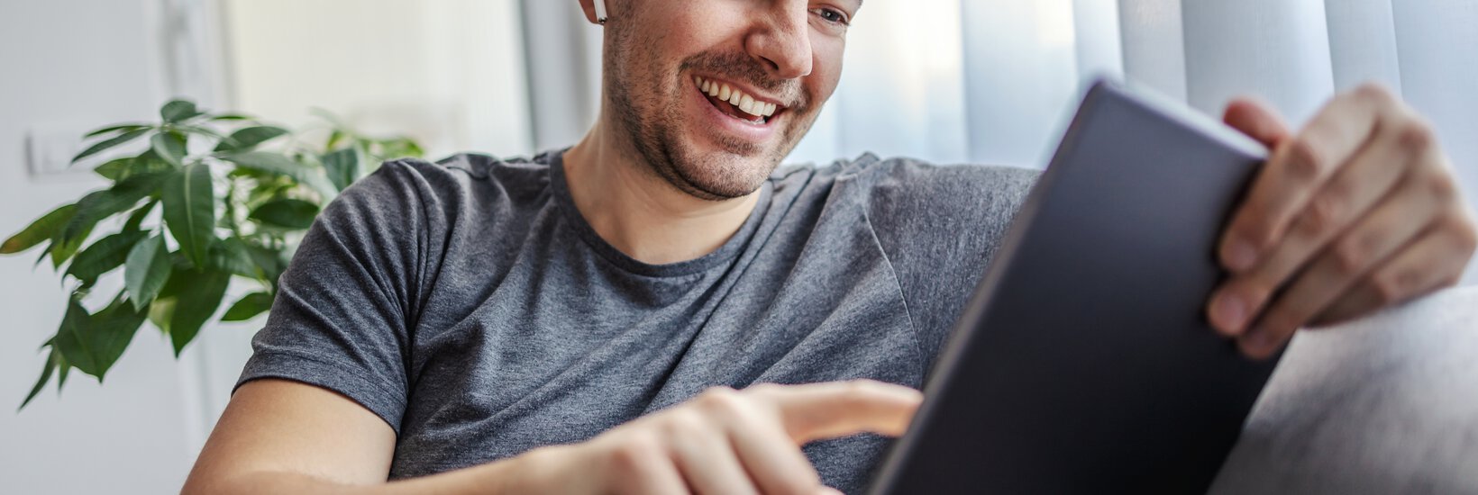 Mann mit Tablett auf Sofa